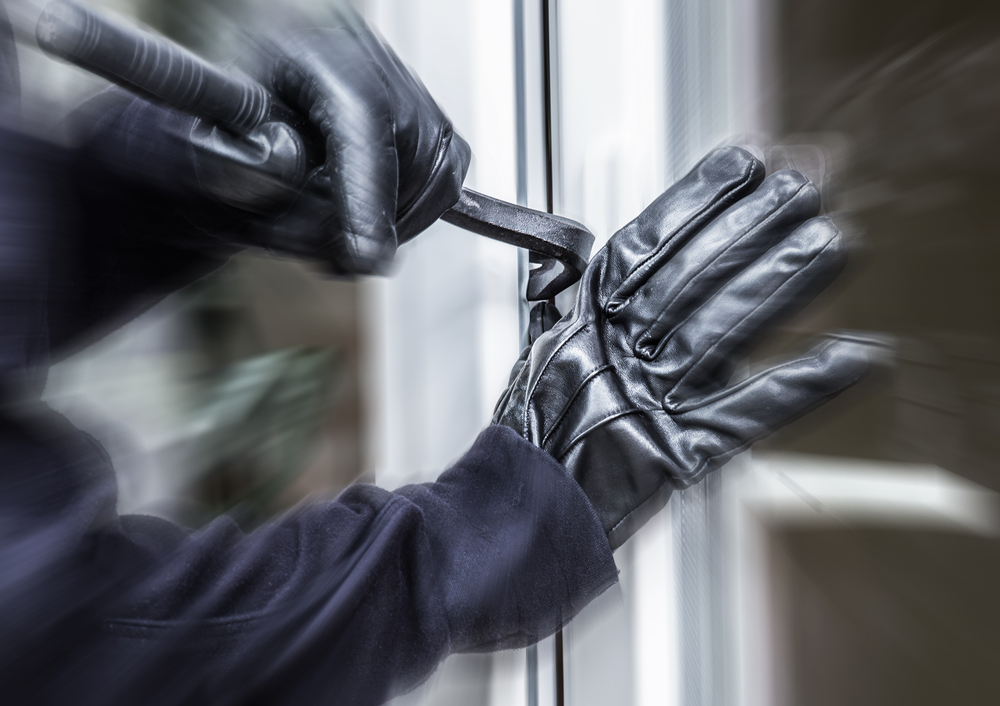 A burglar jimmies open a window